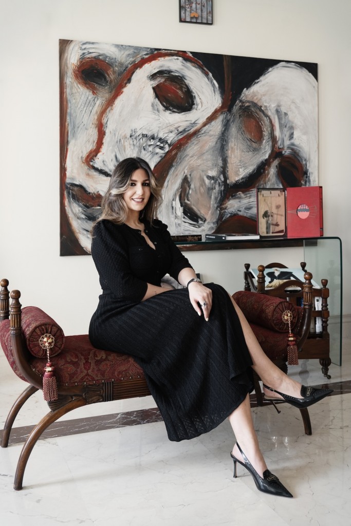 Ava Ayoubi at her home, seated in front of a painting by Shideh Tami. To her right: "Black Box", an art book and a painting by Nasser Bakhshi. Photo: Atoosa Alebouyeh