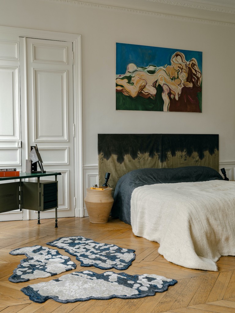 Sophie's bedroom in her Parisian apartment: bedhead by SDA, totem side tables by SDA, 60s leather & metal lamps by Gino Sarfatti for Arteluce, set of rugs meteor by SDA (staron edition), vintage desk BBPR for Olivetti, on it metal sculpture by Marc Leschelier, Sophie’s husband; and painting by Ana Karkar. Photo: Christophe Coenon.