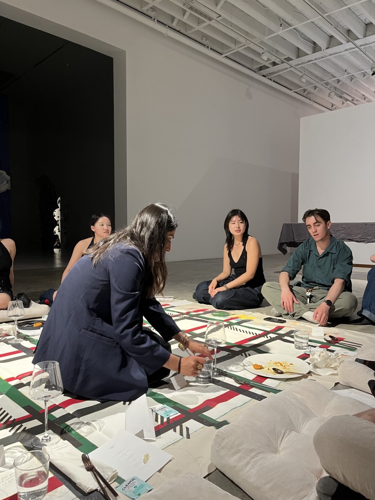 Artist Hafsa Nouman drawing on her work "Dastarkhwaan" (2024) at dinner