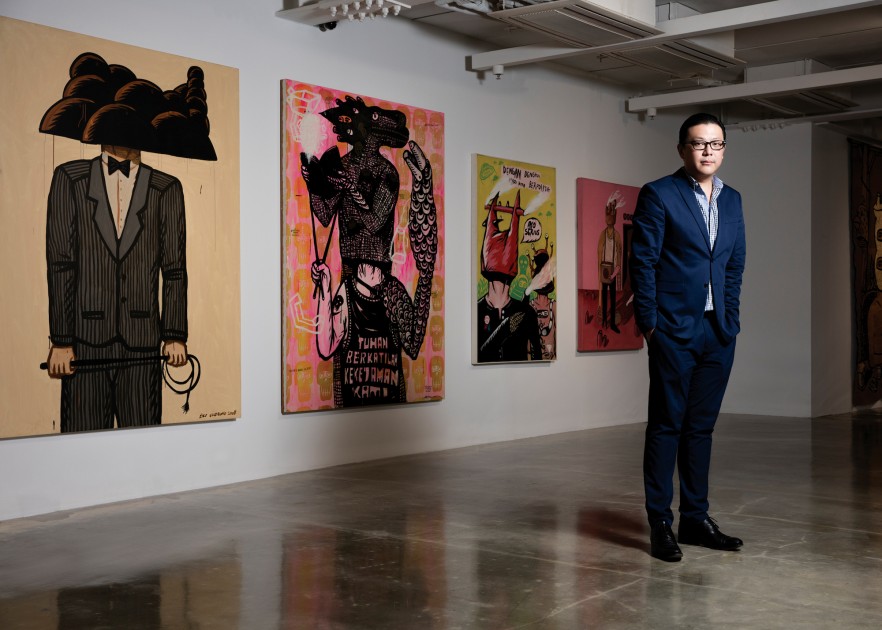 Tom Tandio standing in front of works by Eko Nugroho. Courtesy of Tom Tandio.