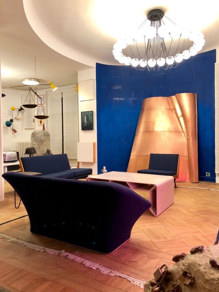 Copper sculpture by Danh Vo, Blue Wall and Carpet Border by Latifa Echakhch, alongside design pieces: « Cellae » Coffee Table by François Bauchet, sofa by Pierre Paulin, chandelier by Gino Sarfatti - Vintage Piece. Courtesy of Clémence and Didier Krzentowski.